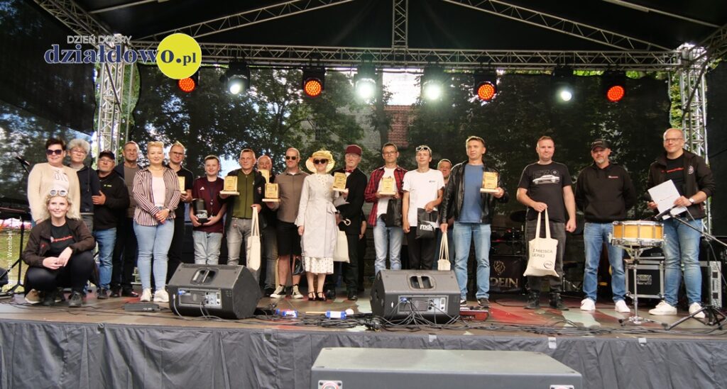 pamiątkowa fotografia wyróżnionych i nagrodzonych podczas X Zlotu Pojazdów Zabytkowych wraz z przedstawicielami organizatorów i przyjaciółmi na scenie w Parku HDK w Działdowie